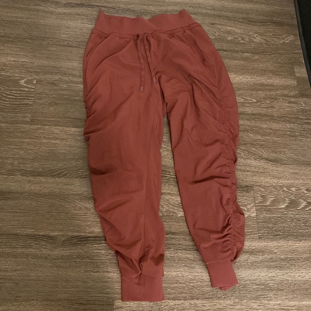 Athleta burnt orange lined rouched joggers with drawstring tie.